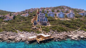 Um resort à beira-mar com vários edifícios, um litoral rochoso e águas azul-claras.
