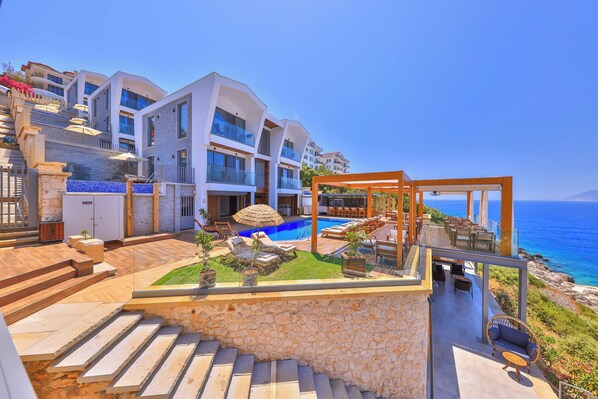 A modern hotel with a pool, outdoor seating, and a view of the sea. - Casa Bi (Kas)