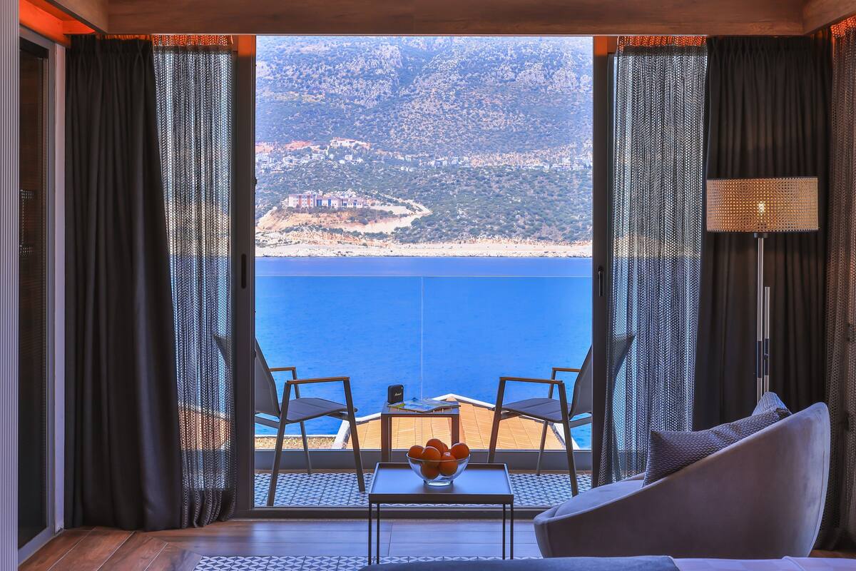 Una habitación con vista al mar, una mesa con un frutero y dos sillas.