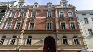 Un edificio de varios pisos con fachada simétrica, ventanas amplias y una entrada central con un arco decorativo.