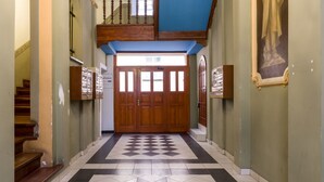 Un pasillo con suelo a cuadros, puertas de madera y una escalera a la izquierda.