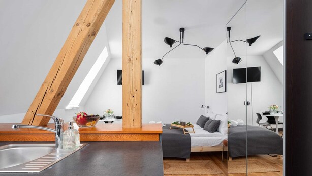 Un dormitorio estilo loft moderno con tragaluces, una zona de cocina con pileta y una viga de techo de madera.