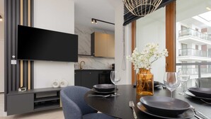 Un comedor moderno con una mesa redonda, platos negros y un jarrón de flores blancas.