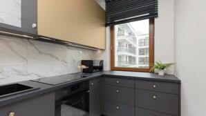 Una cocina moderna con encimera negra, horno empotrado y ventana con vista a un edificio.