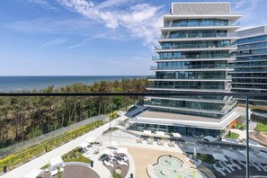 Um hotel moderno com vários andares, um terraço no topo e vista para o mar.