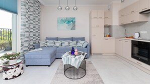 A modern living room with a sofa, a coffee table, and a kitchen area with cabinets and appliances. - Modern Apartment with Terrace | Close to the Beach | Parking. (Jastrzebia Góra)