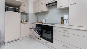 A modern kitchen with built-in appliances, including a microwave, oven, and dishwasher, and a countertop with a coffee machine and a pineapple. - Modern Apartment with Terrace | Close to the Beach | Parking. (Jastrzebia Góra)