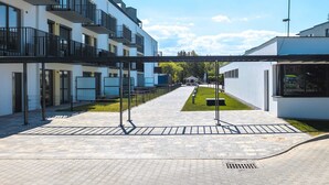 A modern building with multiple balconies, a paved courtyard, and a small garden area. - Modern Apartment with Terrace | Close to the Beach | Parking. (Jastrzebia Góra)