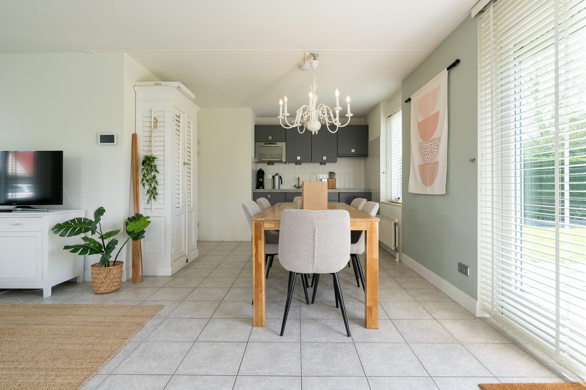 Una cocina moderna con comedor, televisión y candelabro.