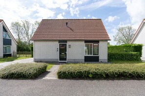 A two-story residential building with a tiled roof, a front door, and a small window.