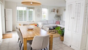 A dining area with a wooden table and chairs, a sofa, and a large white wardrobe.