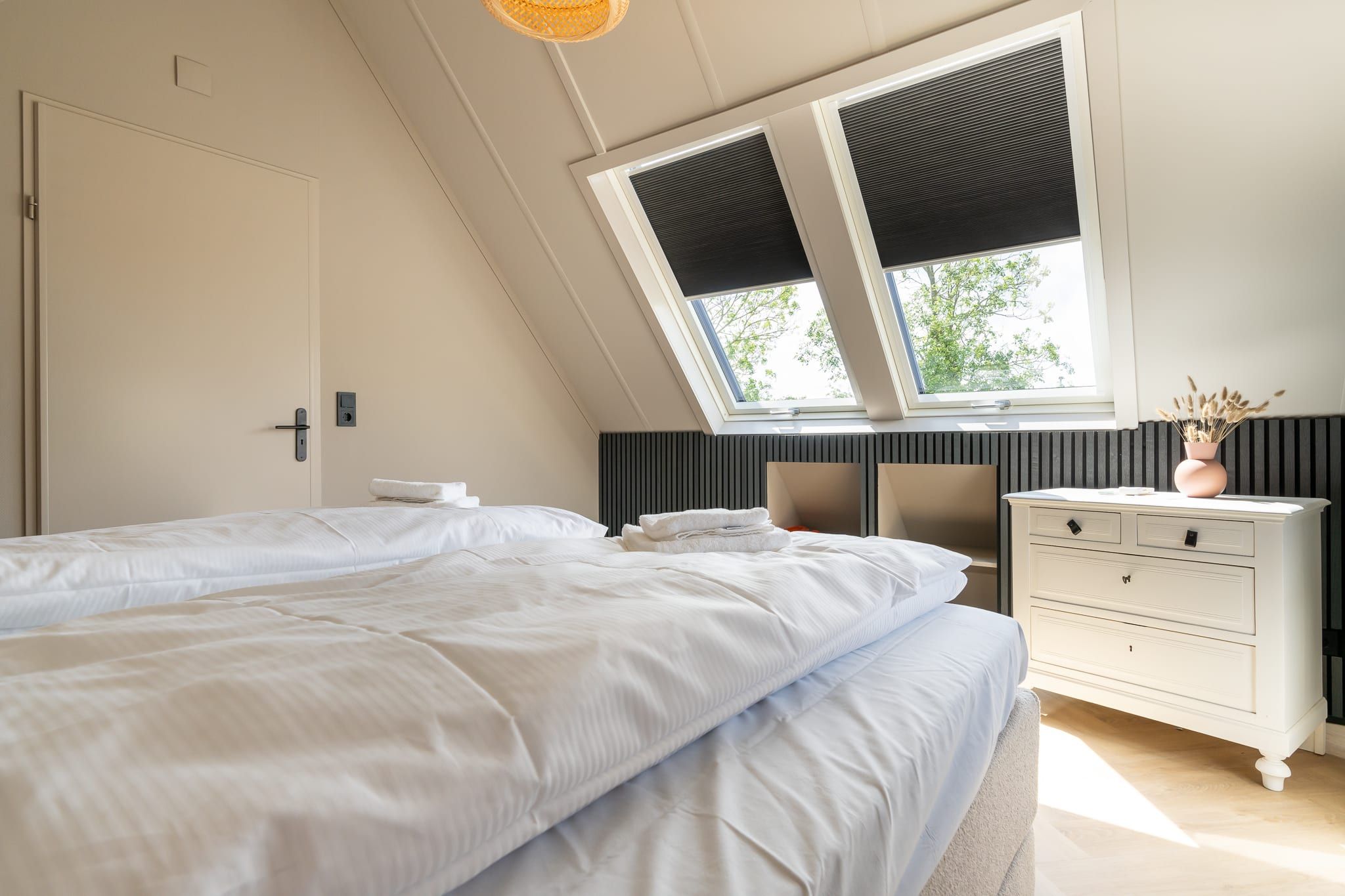 Une chambre à coucher avec un lit, une commode, une fenêtre avec des stores et un ventilateur de plafond.