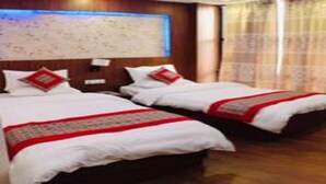 A hotel room with two beds, wooden flooring, a large wall map, and a window with curtains. - MeroStay 256 Hotel Mai (Kathmandu)