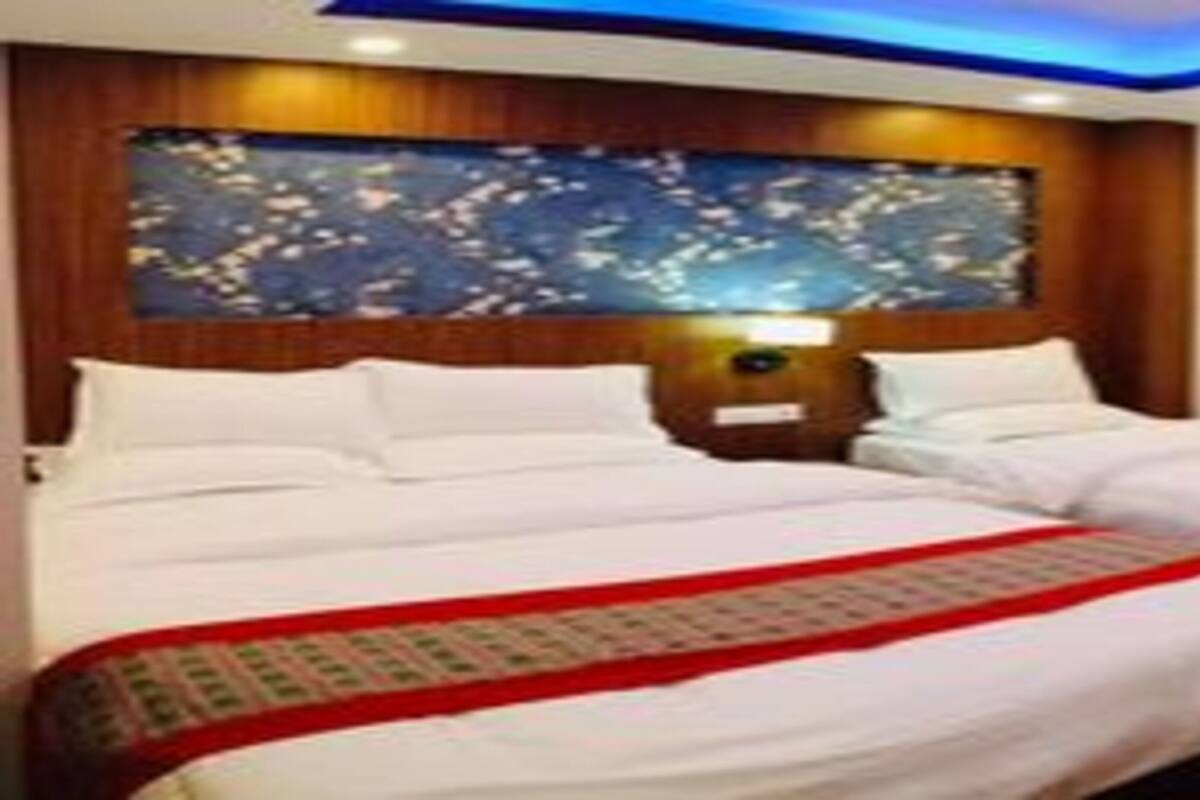 Une chambre d’hôtel avec deux lits, une tête de lit en bois et un panneau décoratif mural.