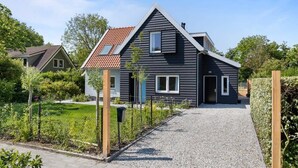 Una casa moderna su due piani, con vialetto sterrato e giardino recintato.