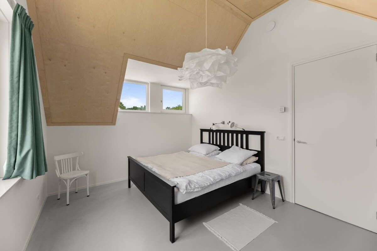 Une chambre à coucher avec un lit, une fenêtre, une chaise et une porte.