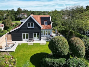 A modern two-story house with a dark exterior, a red-tiled roof, and a well-maintained lawn. - Spacious holiday home with enclosed garden in Domburg | Casembrootplein 19 (Domburg)