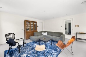 A living room with a sectional sofa, a coffee table, a cabinet, and two chairs.
