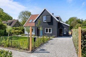 A modern two-story house with a gravel driveway and a fenced garden. - Spacious holiday home with enclosed garden in Domburg | Casembrootplein 19 (Domburg)
