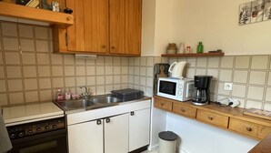 Una cocina compacta con estufa, microondas, lavaplatos y un bote de basura.
