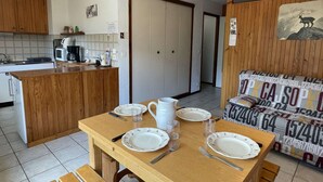 Una cocina acogedora con armarios de madera, una mesa de comedor preparada para cuatro personas y un sofá con un diseño estampado.
