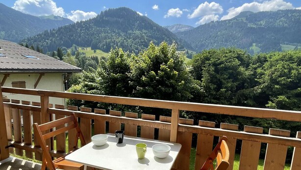Un balcón con mesa y sillas, con vistas a un paisaje montañoso.