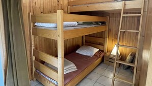 Habitación con literas, paredes de madera y una escalera.