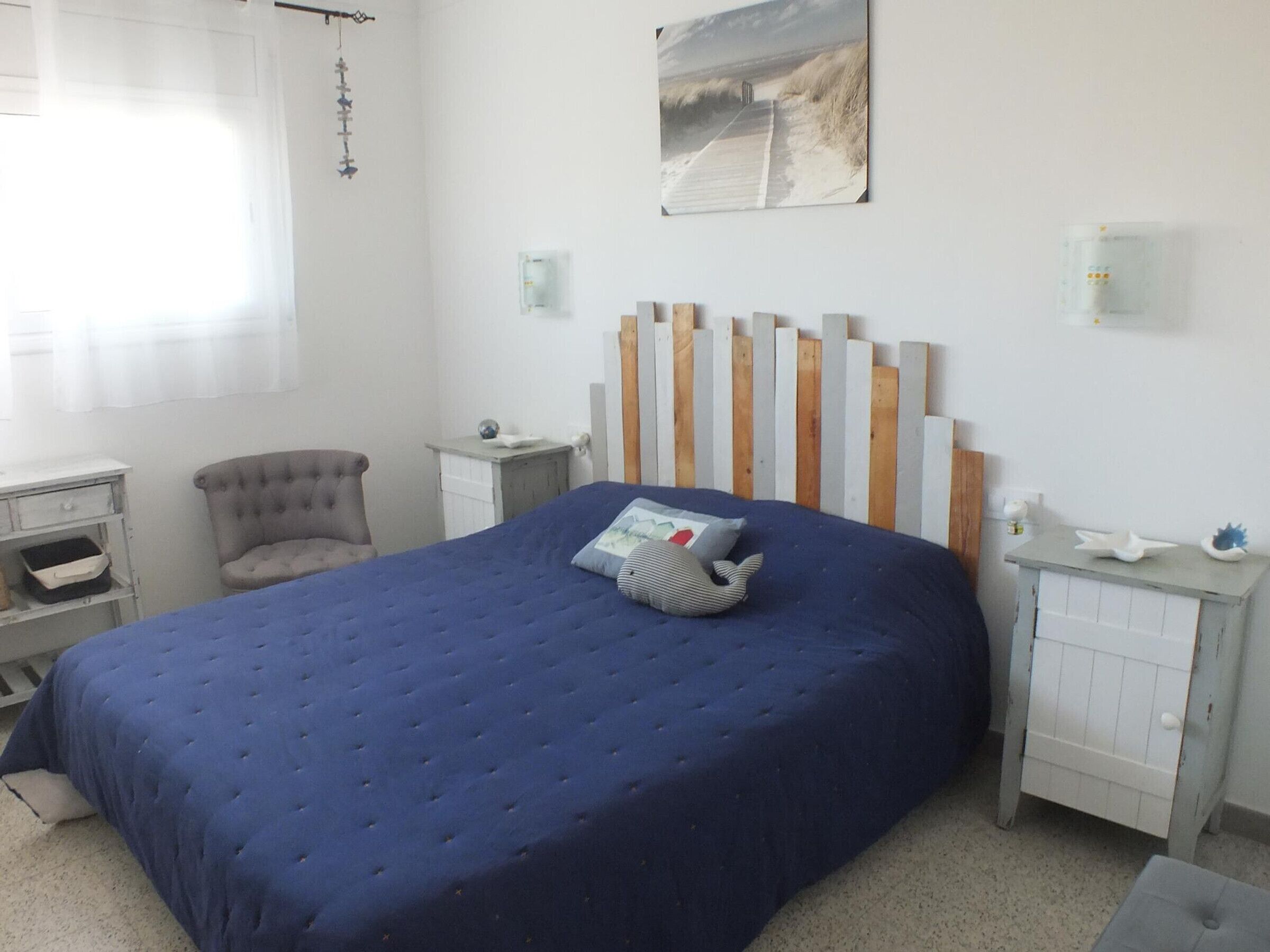 A bedroom with a large bed, a chair, a desk, and a nightstand.