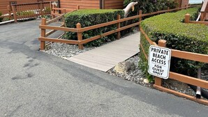 Segnaletica per accesso esclusivo a spiaggia privata, recinzioni in legno e un sentiero che conduce a un'area spiaggia.