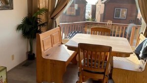 Zona pranzo con tavolo e sedie in legno, una pianta in vaso e vista mare attraverso ampie finestre.