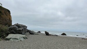 Una spiaggia sabbiosa con grosse rocce e una scogliera.