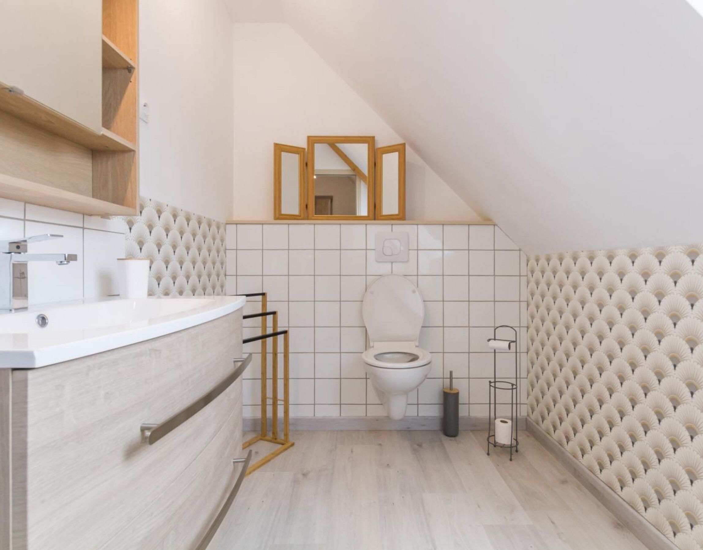A modern bathroom with a white toilet, a vanity with a mirror, and a towel rack.
