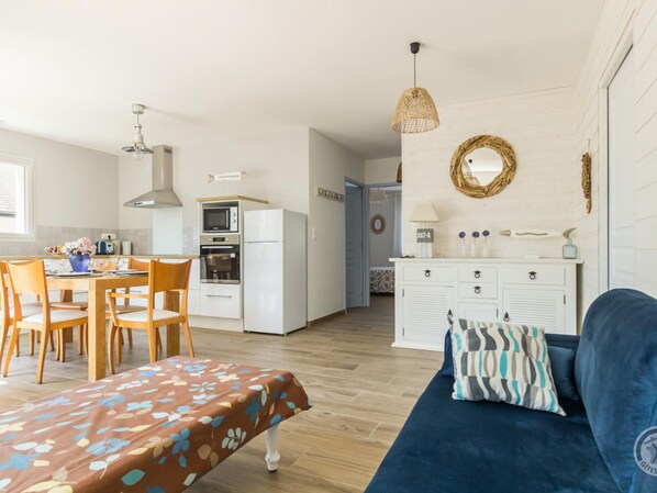 A compact living space with a dining area, kitchenette, and a sofa with a patterned throw.