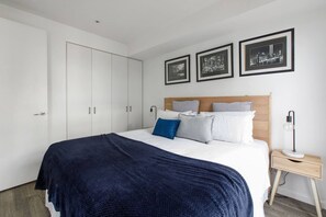 Quarto moderno com uma cama grande, um guarda-roupa e três quadros na parede.