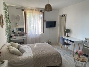 Relax in a serene space with a large bed, desk, and TV, surrounded by a minimalist design.
