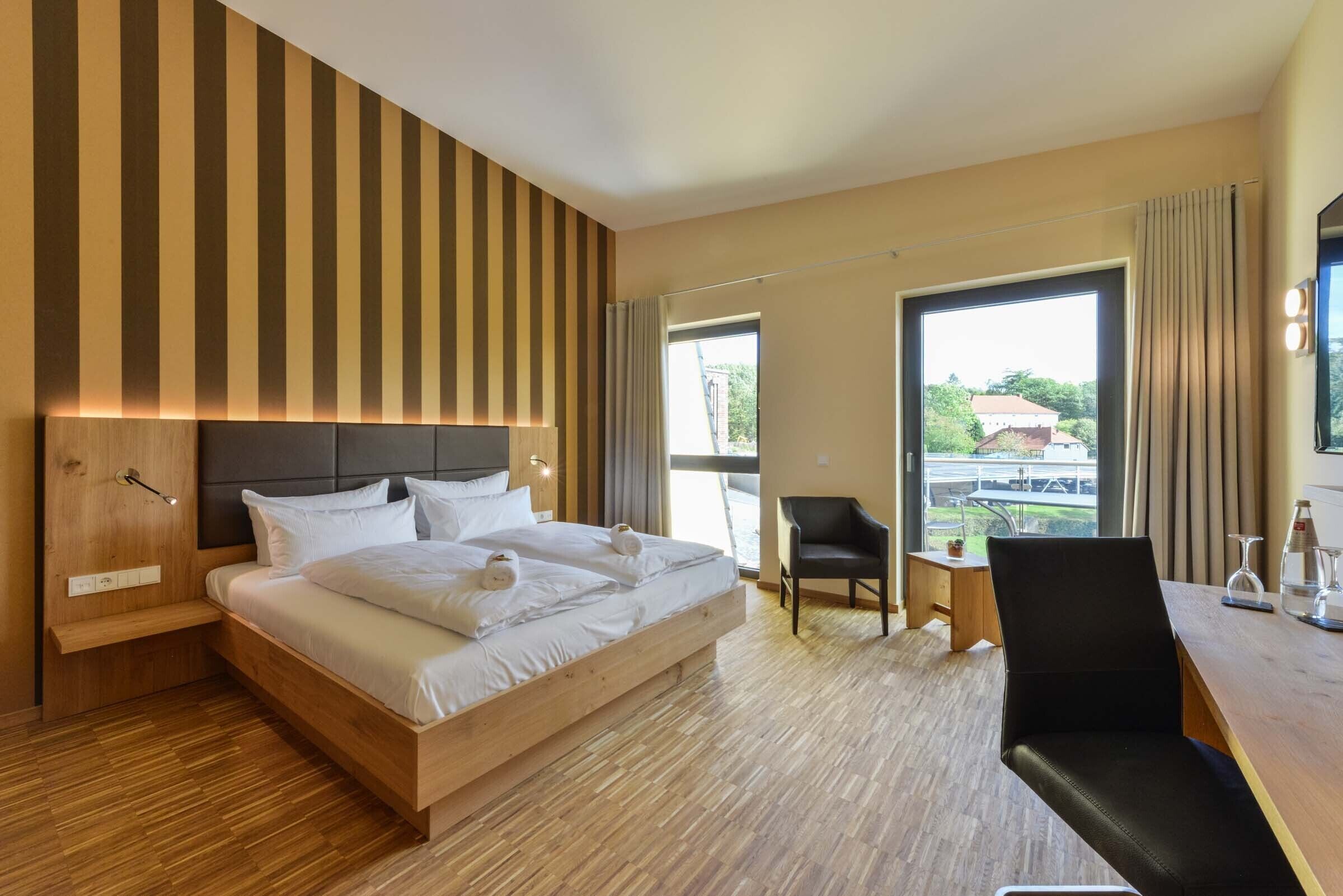 Een moderne hotelkamer met een houten bed, een bureau en een stoel.