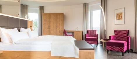Une chambre d’hôtel moderne avec un lit en bois, un bureau, une chaise et une grande armoire.