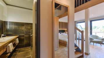 Un baño moderno con un lavamanos grande, baldosas oscuras y un mueble de tocador de madera.