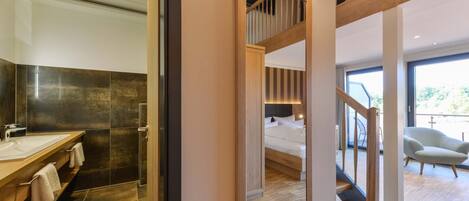 Un baño moderno con un lavamanos grande, baldosas oscuras y un mueble de tocador de madera.