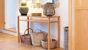 A wooden console table with a lamp, a mirror, and baskets. - The Coach House at Jervaulx (Ripon)