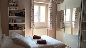 A bedroom with a bed, a bookshelf, a window with curtains, and a mirror. - La Talonnière, Maison de Village Avec Terrasse (Messas)