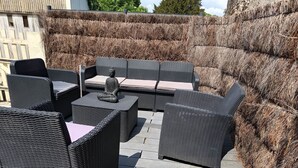 An outdoor patio with wicker furniture, including sofas and a table, surrounded by a wooden deck. - La Talonnière, Maison de Village Avec Terrasse (Messas)