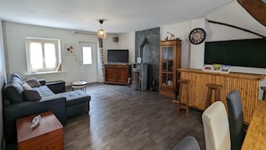 A living room with a sofa, a wooden cabinet, a television, and a fireplace. - La Talonnière, Maison de Village Avec Terrasse (Messas)
