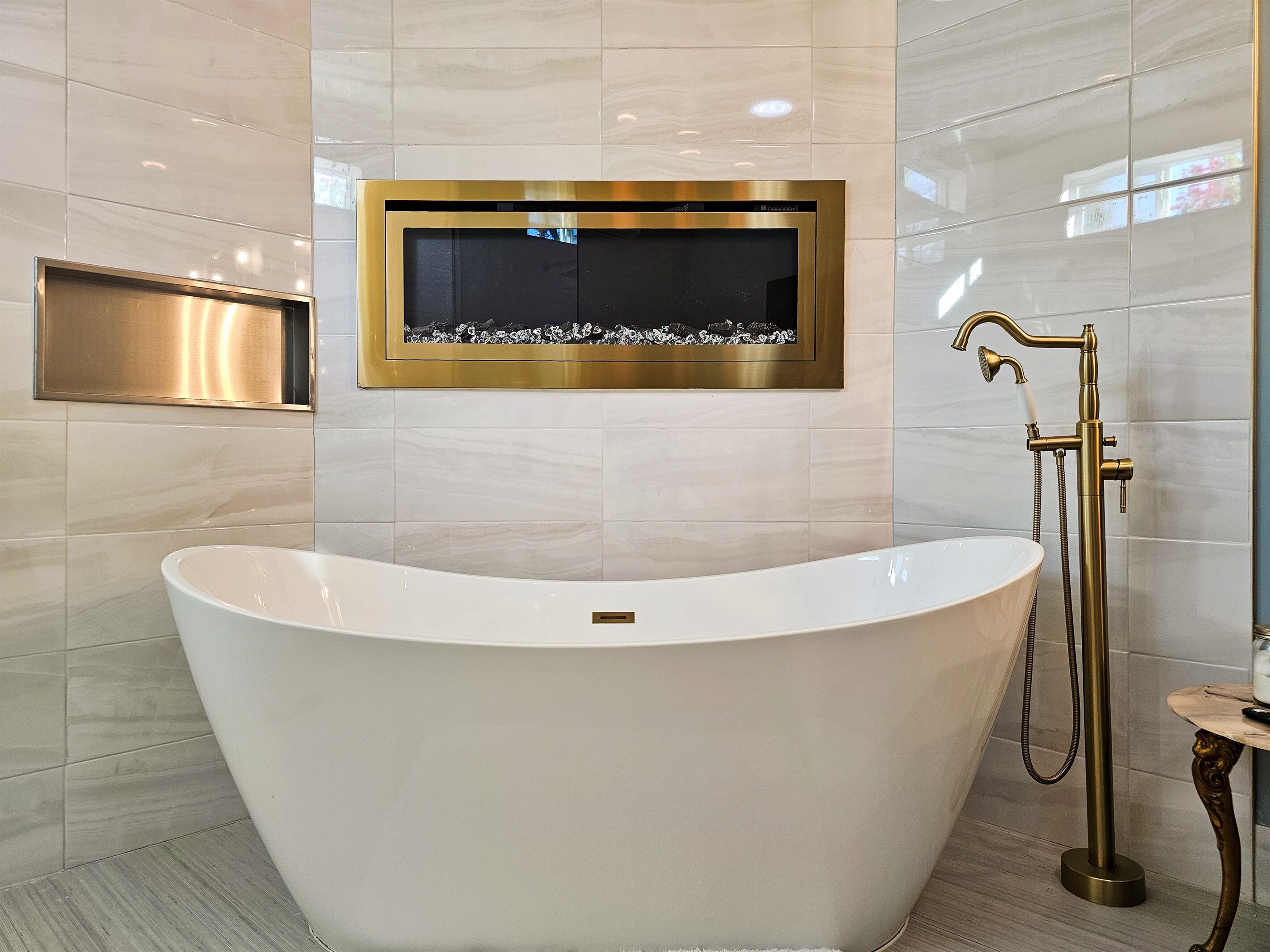 A modern bathroom with a freestanding bathtub, a wall-mounted mirror, and a shower with a gold faucet.