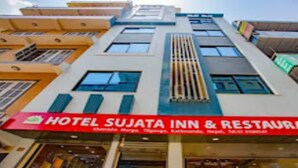 Un hotel de varios pisos con un llamativo letrero rojo que dice Hotel Sujata Inn & Restaurant.