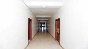 Un pasillo largo y estrecho con paredes blancas y piso de baldosas.