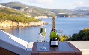 A bottle of Bollinger champagne and a glass on a wooden tray, overlooking a scenic coastal view. - Zavia Alpha in Syvota (Igoumenitsa)