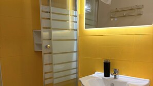 Une salle de bain avec une douche à parois de verre, un lavabo blanc et un miroir.