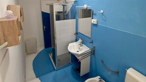 Une salle de bain équipée d’une douche, d’un lavabo, d’un bidet et de toilettes.