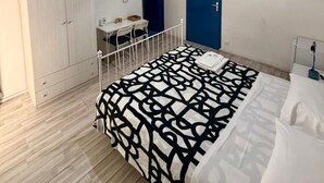 Une chambre à coucher avec un lit, un bureau, une armoire, une télévision et un tableau.
